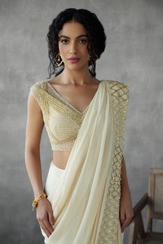 Cream saree in georgette crepe base with sequin, pearl drop, gold sequin border embellished saree. Paired with sleeveless jaal embroidered V neck padded blouse.
Components: 2
Pattern: Embroidery
Type Of Work: Jaal, Beads, Pearls, Sequin
Neckline: V Neck
Sleeve Type: Sleeveless
Fabric: Saree: Georgette Crepe, Blouse: Tulle
Color: Cream, Beige
Other Details: 
Attached inner lining
Padded blouse
Approx. weight: 3kgs
Length:
Saree : 44inches
Blouse : 13inches
Occasion: Sangeet, Mehendi and Haldi - A Elegant Chinon Blouse With Resham Embroidery, Festive V-neck Georgette Blouse Piece, Elegant Chinon Blouse With Zari Work, Elegant Chinon Blouse Piece For Reception, Elegant V-neck Choli With Mirror Work, Elegant Wedding Blouse In Chinon, Elegant Chinon Blouse For Wedding, Elegant V-neck Pre-draped Saree For Festive Occasions, Embellished V-neck Blouse For Reception