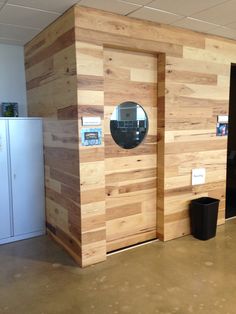 a room with wood paneling and a mirror on the wall next to a trash can