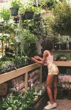 a woman is looking at plants in a greenhouse