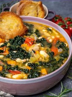 a bowl of vegetable soup with bread on the side