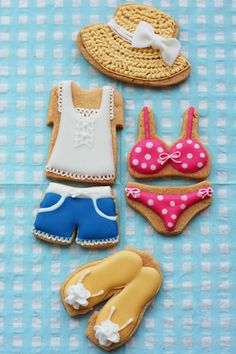 some cookies are laying out on a blue and white checkered tablecloth with hats, swimsuits, and flip flops