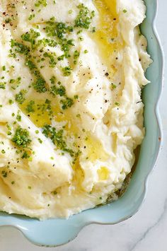 mashed potatoes with parsley in a blue dish on a marble countertop, ready to be eaten