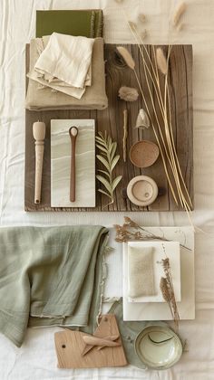 various items are laid out on a bed with white linens and green napkins