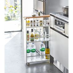 a kitchen with an oven, dishwasher and shelves filled with bottles on the floor