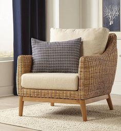 a wicker chair with two pillows on top of it in front of a window