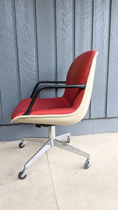 a red and white office chair sitting on top of a cement floor