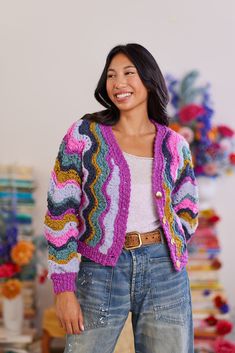 a woman is smiling and wearing a colorful cardigan