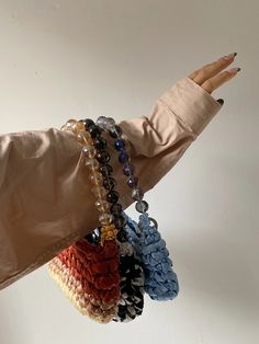 a woman's hand holding several bracelets with beads on each wrist and one bead hanging from the other