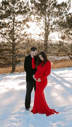 a pregnant couple standing in the snow together