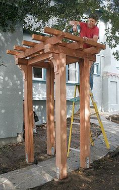 a man standing on top of a wooden structure in the middle of a yard next to a tree