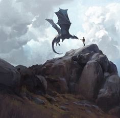 a man standing on top of a rocky hill next to a dragon flying over him