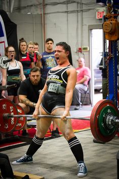 a man holding a barbell during a crossfit competition with other people watching