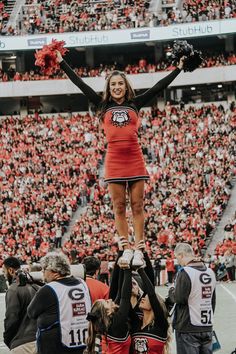 a cheerleader standing on the back of a football player in front of an audience