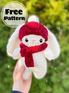 a hand holding up a small crocheted stuffed animal with a red scarf around it's neck