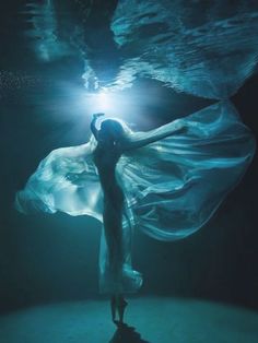 a woman in a flowing dress under water