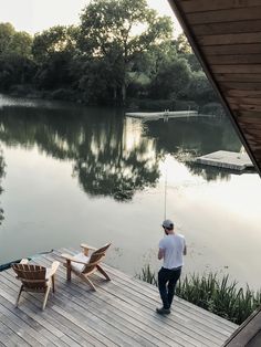 a man standing on top of a wooden dock next to a lake