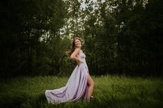 a woman in a long dress is standing in the grass and smiling at the camera