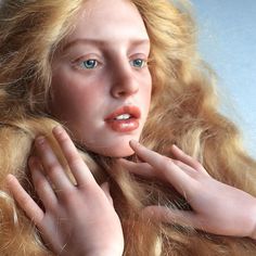 a doll with blonde hair and blue eyes holding her hands to her face while looking at the camera