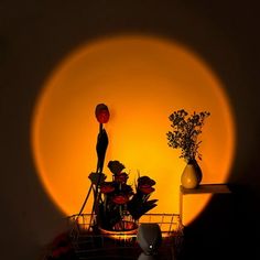 a basket with flowers in it sitting next to a vase and lamp on a table