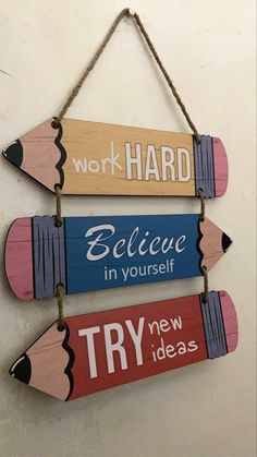 three wooden pencils hanging on a wall with the words work hard, believe in yourself and try ideas