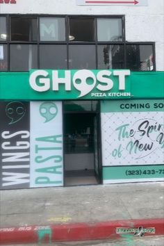 the front of a restaurant that has been painted green and white with ghost lettering on it