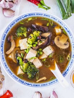 a bowl of soup with tofu, mushrooms and broccoli