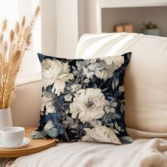 a coffee cup on a tray next to a pillow and some dried flowers in a vase