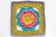 a crocheted square with a flower in the center on a white surface,