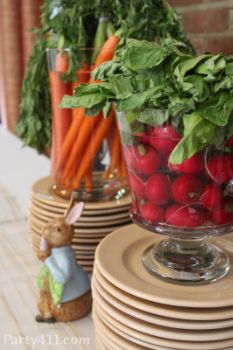 there are many fruits and vegetables in the glass vases on the table with bunny figurines