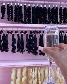 a person holding up a wine glass in front of some hair hanging on a rack