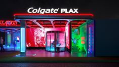 the entrance to colgate plax at night with neon lights and people walking by