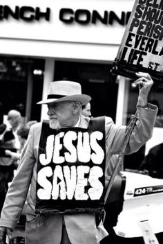 a man holding a sign that says jesus saves