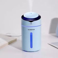 a humidifier sitting on top of a white table next to a laptop and mouse