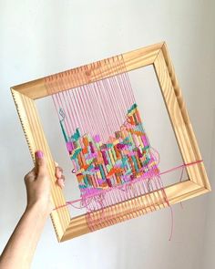 a person is holding up a weaving frame