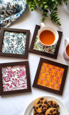 four coasters on a table with tea and cookies