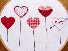 a close up of a embroidery on a piece of cloth with hearts and arrows in it