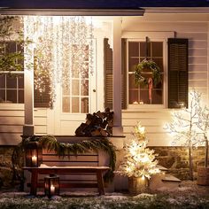 a bench sitting in front of a house with christmas lights on the windows and door