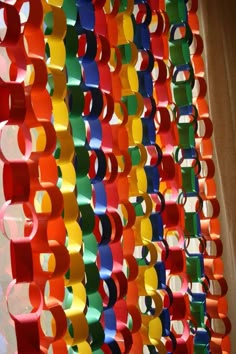 colorful paper circles hanging from the ceiling in front of a white wall with curtains behind them