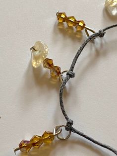 This fashionable delicate bracelet handcrafted with earthy gray thread knots, citrine gemstones and amber glass beads is a bright rustic addition. Citrine gemstones in pale yellow tones add elegance to the subtle glimmer of amber bicone faceted crystal glass beads. Adjust length of the bracelet with included jump rings. Gemstone - Citrine Beads - Bicone faceted crystal glass beads Color - Pale yellow, amber Bracelet closure - Lobster claw Other materials - Gray beading thread, metal jewelry pins Adjustable Beaded Yellow Crystal Bracelet, Adjustable Yellow Beaded Crystal Bracelet, Adjustable Amber Crystal Bracelet With Gemstone Beads, Adjustable Beaded Citrine Jewelry, Adjustable Yellow Crystal Bracelet With Gemstone Beads, Adjustable Amber Crystal Bracelet With Natural Stones, Adjustable Citrine Gemstone Beads Crystal Bracelet, Adjustable Yellow Citrine Crystal Bracelet, Adjustable Citrine Beaded Bracelets With Natural Stones