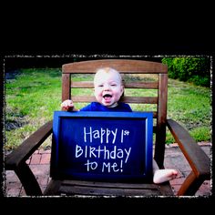 a baby sitting in a chair holding up a birthday sign that says happy 1st birthday to me