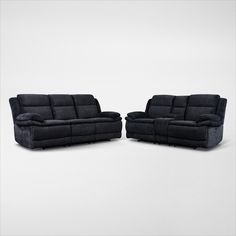 two black reclining sofas sitting next to each other on a white background,