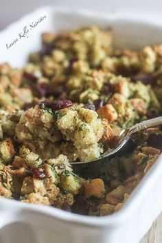 a casserole dish filled with stuffing and crumbled toppings on a wooden table