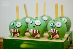 green monster cake pops with yellow sticks sticking out of their mouths and fangs on them