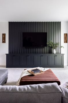 a living room filled with furniture and a flat screen tv mounted on the wall above it