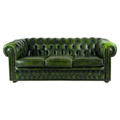 a green leather couch sitting on top of a white floor