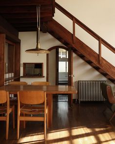 a dining room table and chairs under a wooden staircase