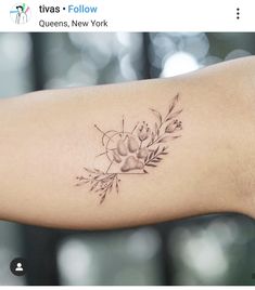 a woman's arm with a tattoo on it that has flowers and leaves around it