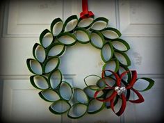 a paper wreath hanging on a door with red and green ribbons attached to the front