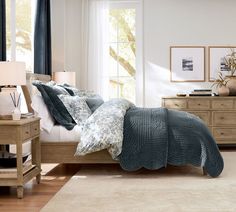 a bed room with a neatly made bed next to a night stand and dressers