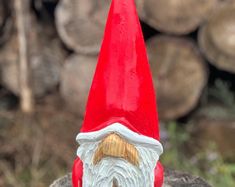 a red and white gnome statue sitting on top of a tree stump